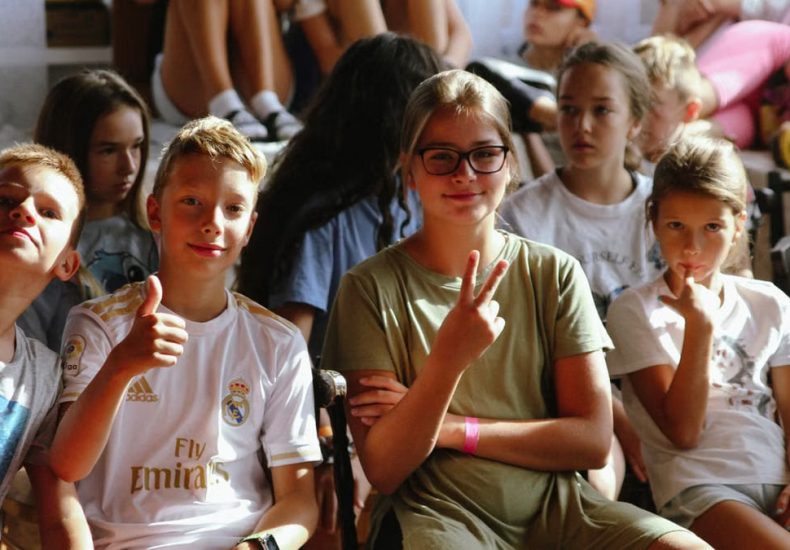 Cheerful group of children sitting together at an indoor event, showcasing friendships and diversity.
